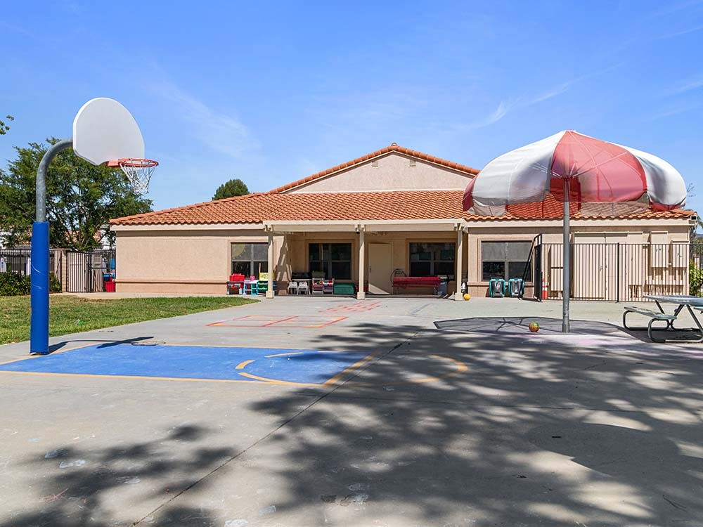 Basketball hoop on a blue court with a building in the background