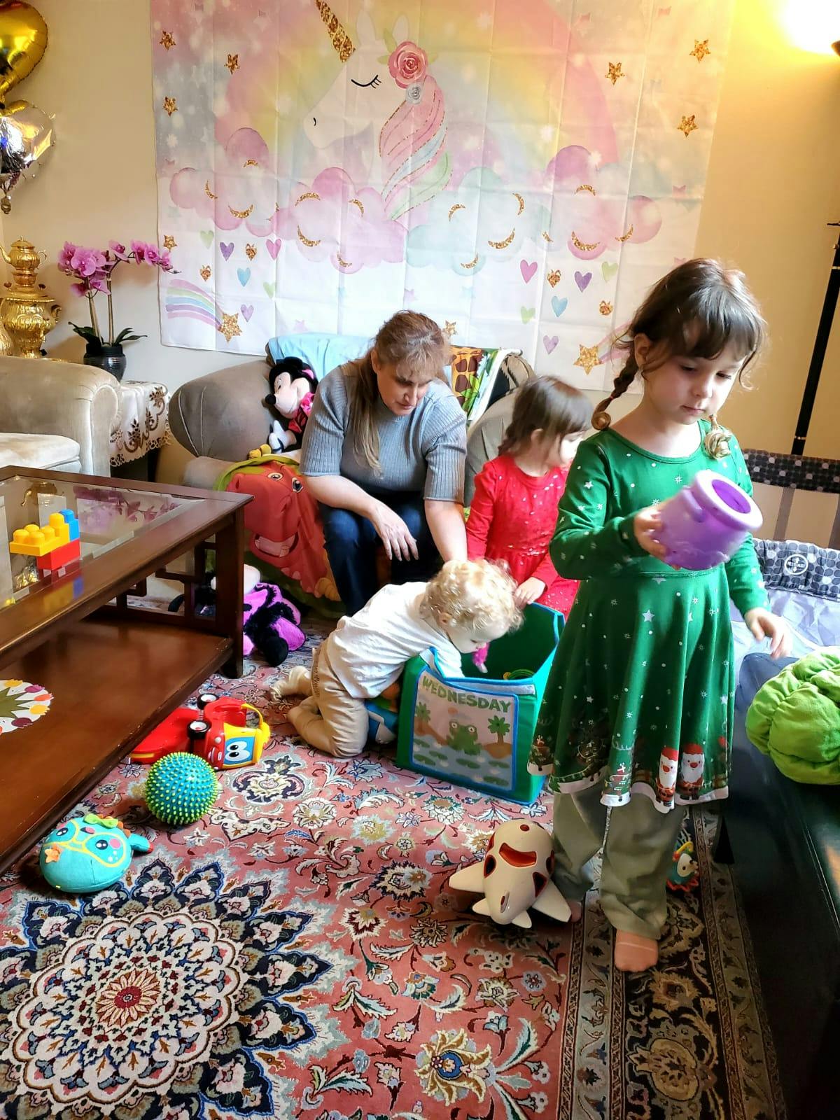 Adult and three children playing with toys on a rug