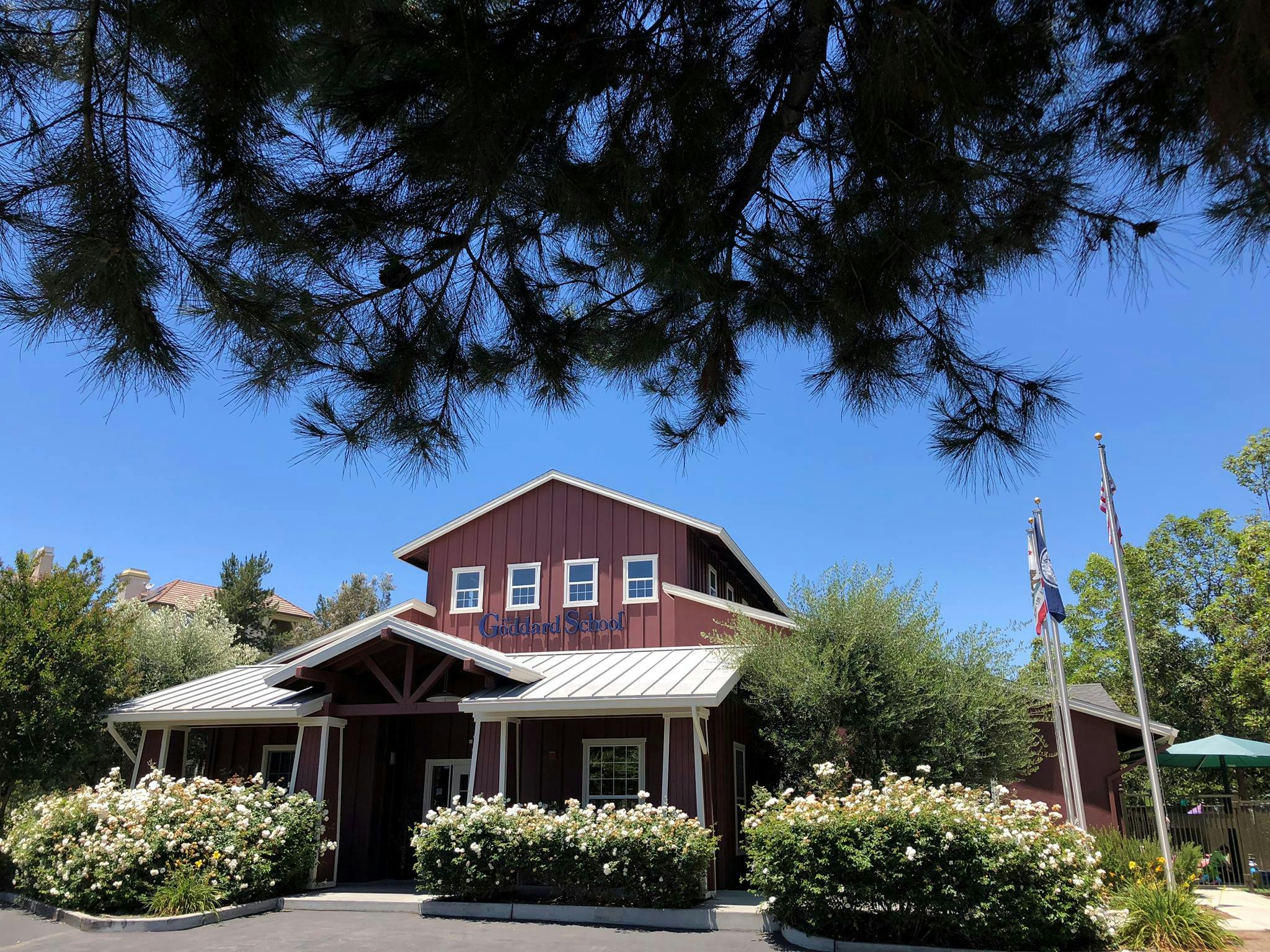 Red barn-style building with white trim and roof, surrounded by green bushes