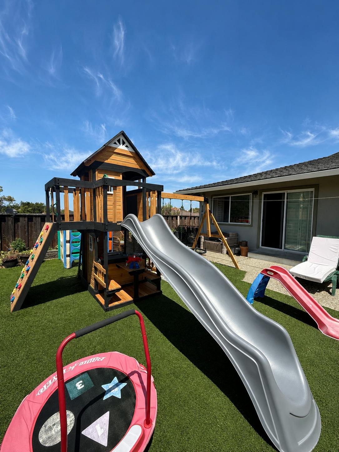 Wooden playground structure with a slide on a backyard lawn