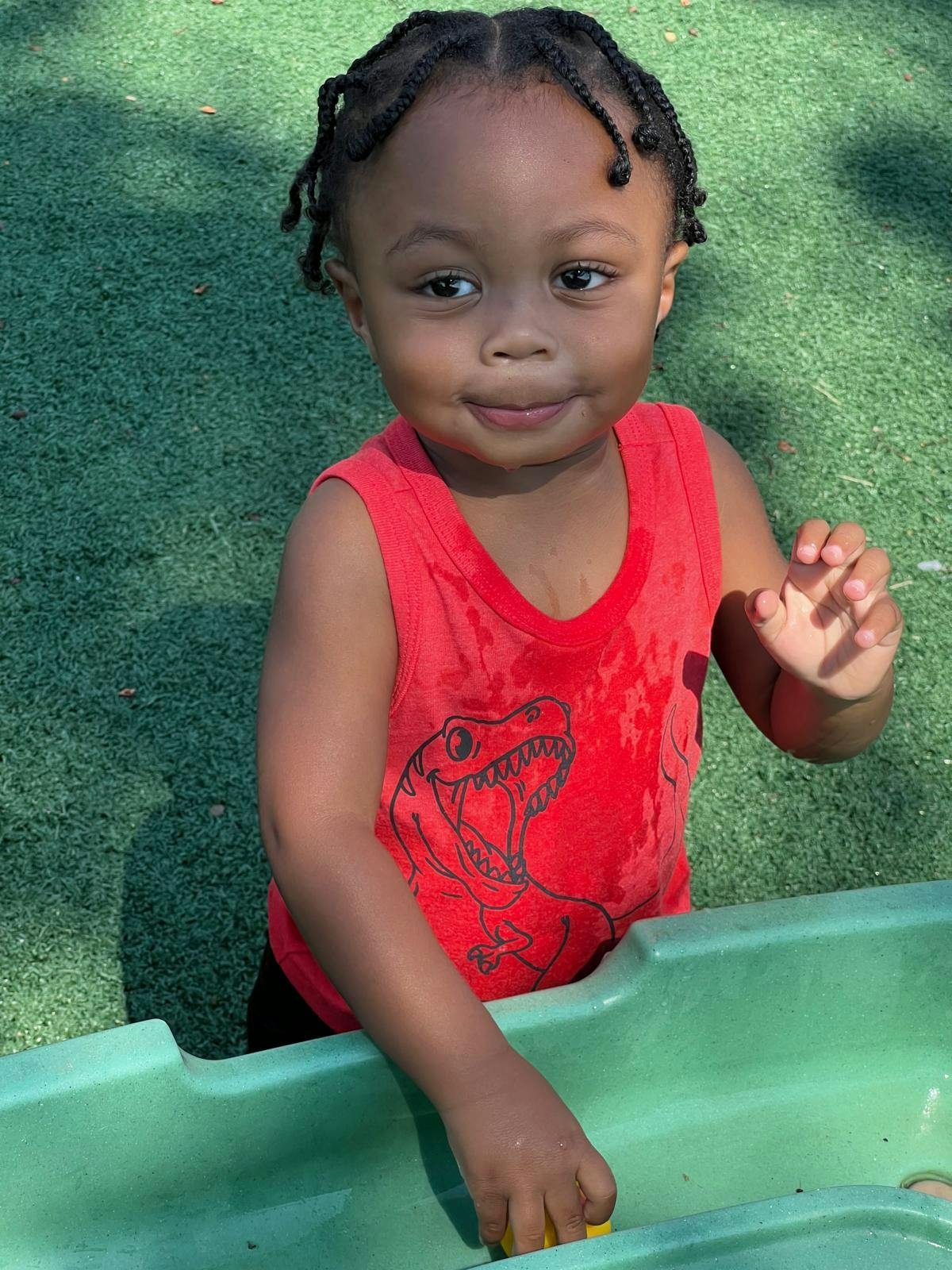 Child in red shirt playing in a green water table