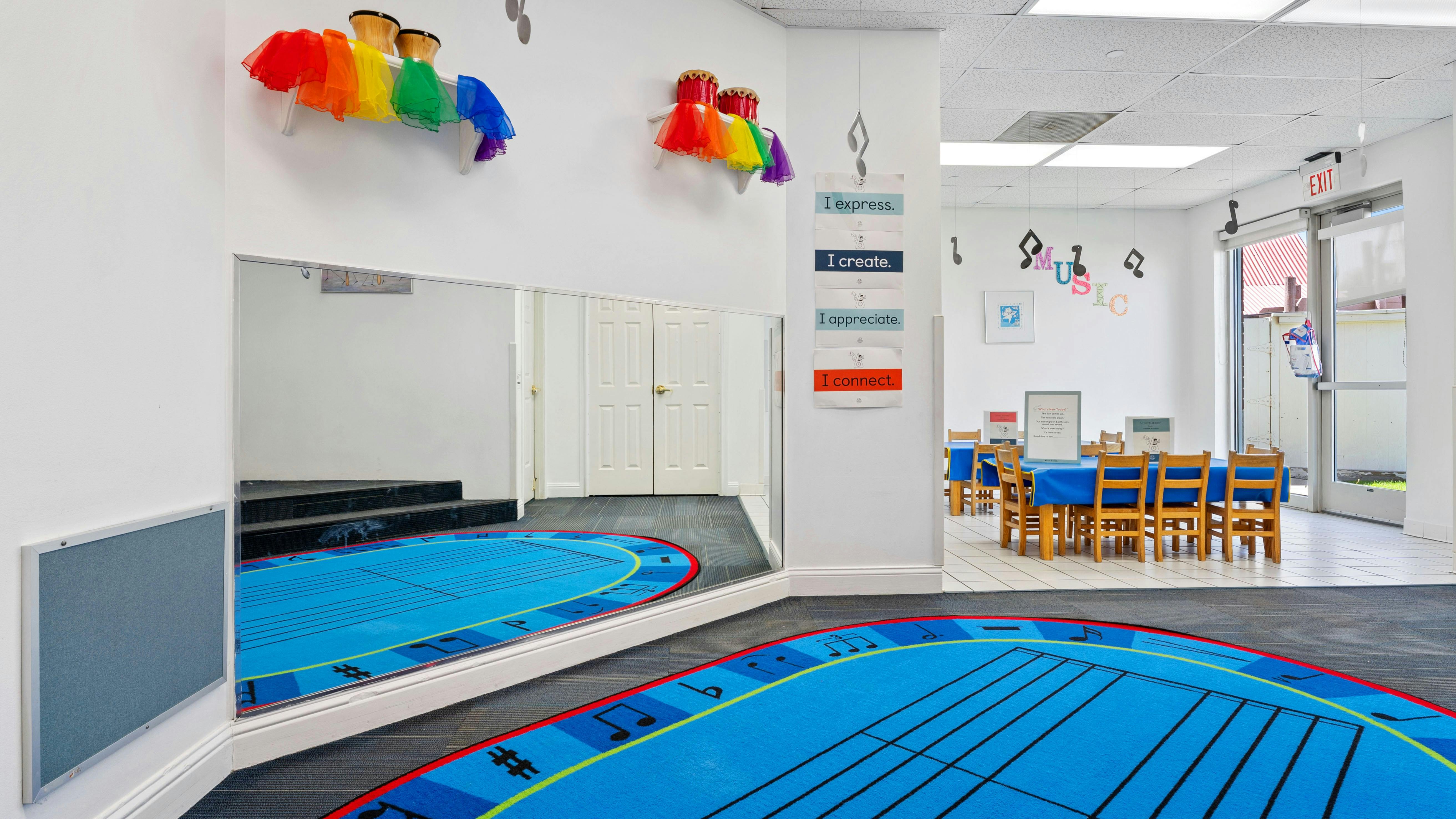 Mirror reflecting blue rug with musical staff, drums with rainbow fabric, and signs on wall