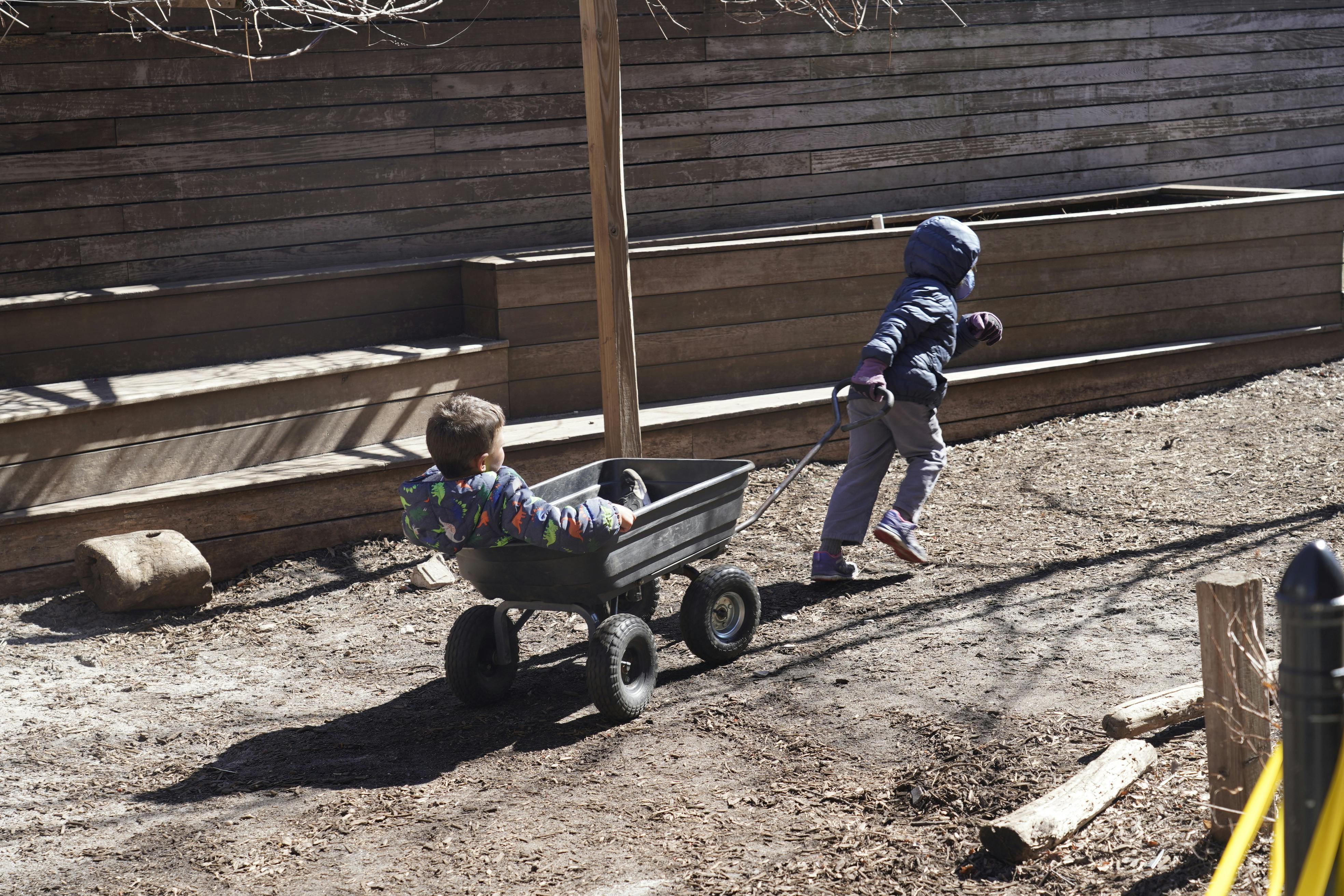 Child pulling another child in a wagon