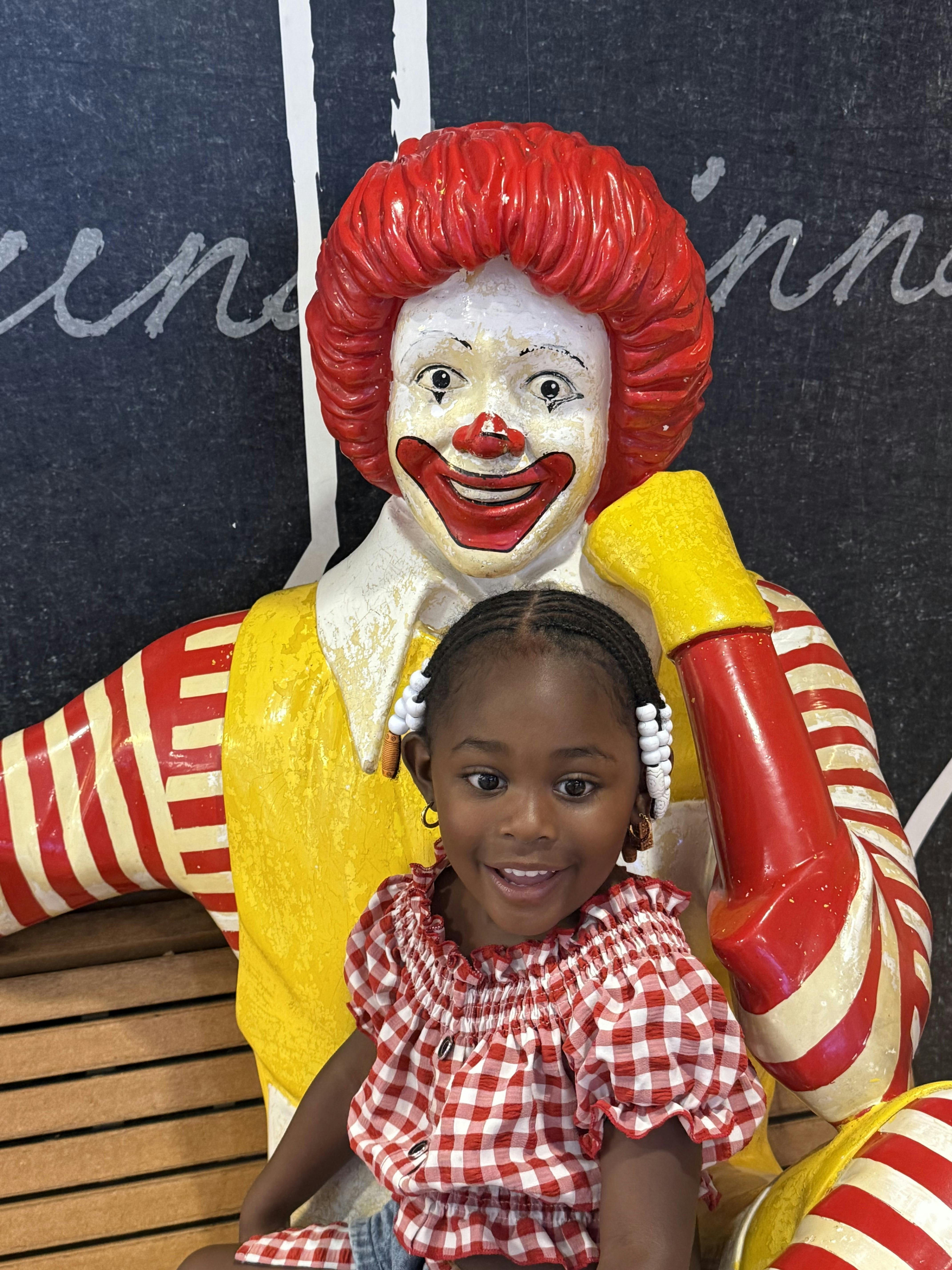 Child sitting in front of a clown statue