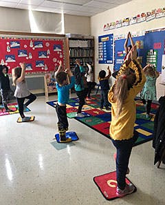 Children doing yoga in a classroom