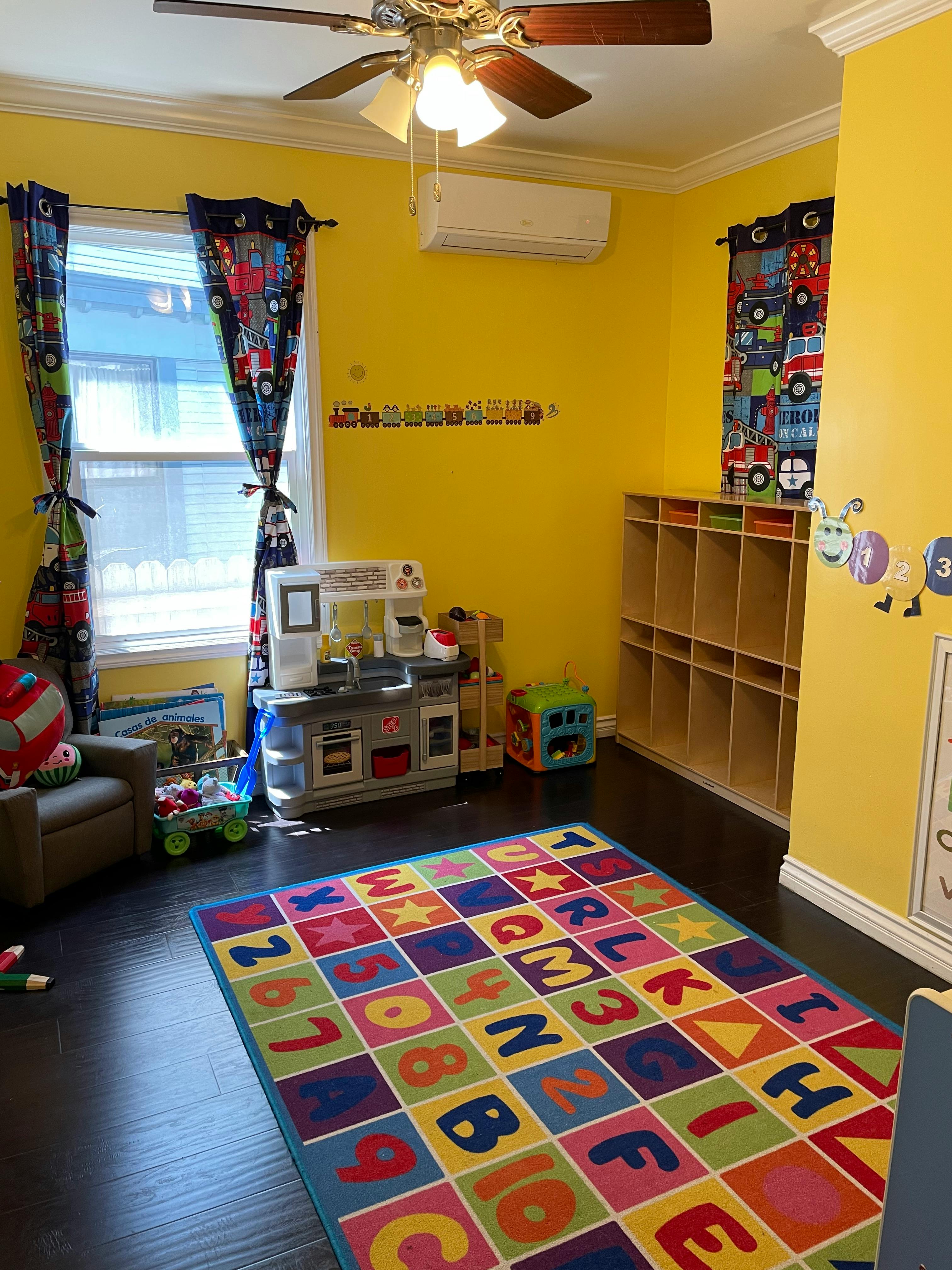 Playroom with a colorful alphabet and number rug, toy kitchen, and cubbies