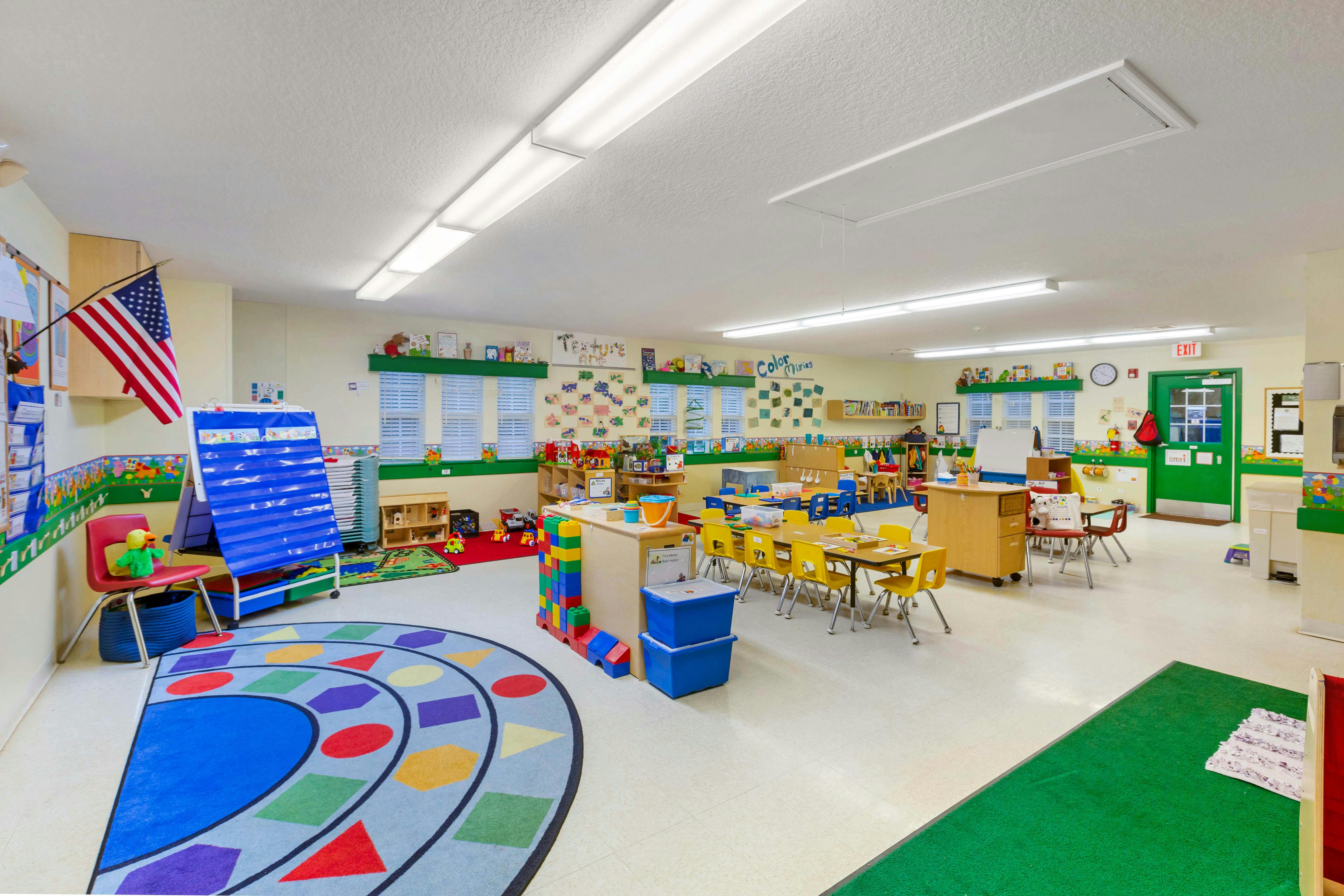 Classroom with tables, chairs, toys, and an American flag