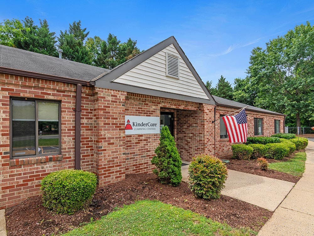 Brick building with a white sign that says "KinderCare Learning Centers" and an American flag