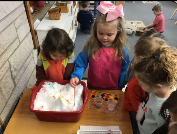 Children playing with colored foam in a red bin