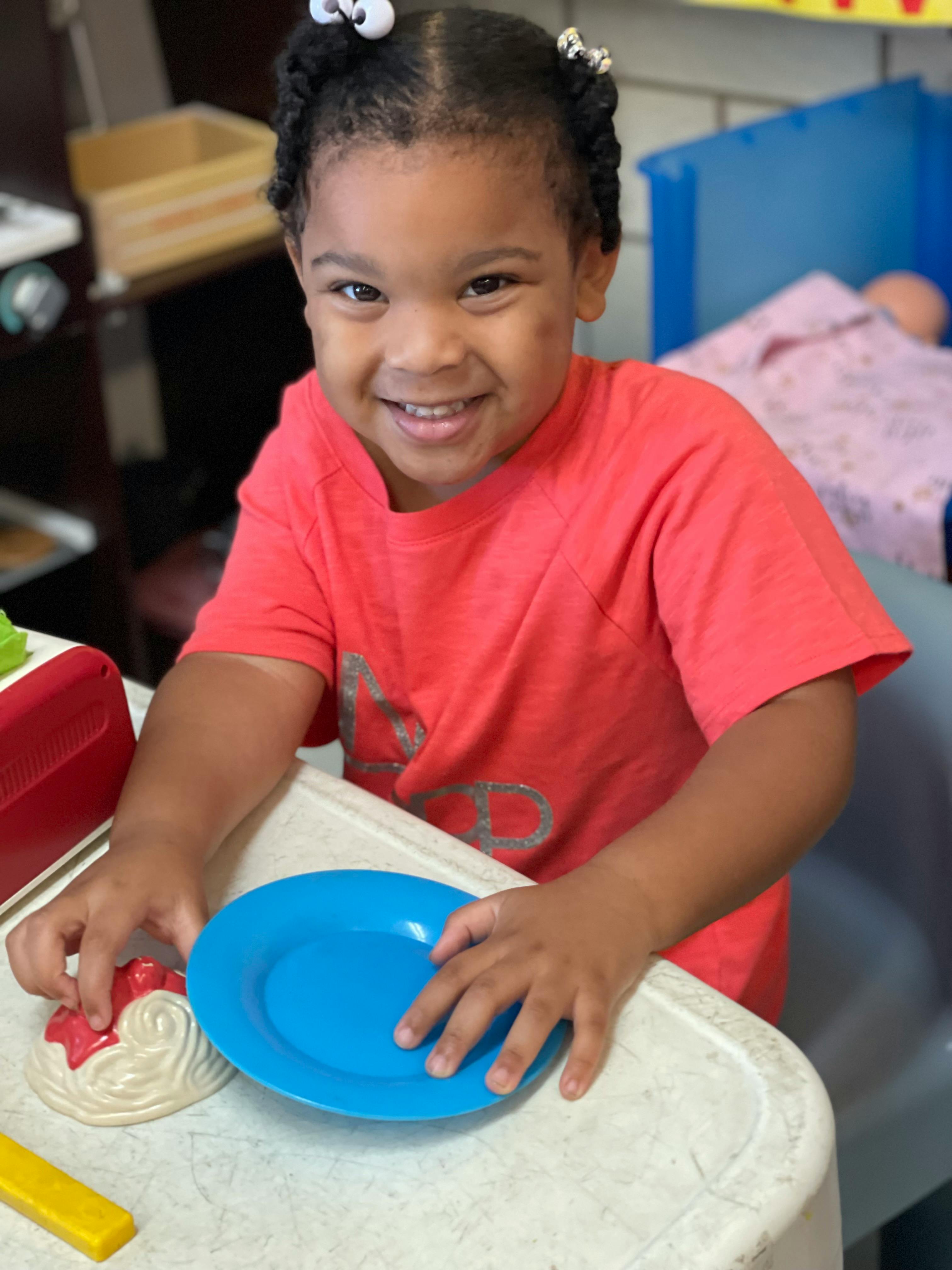 Child playing with a blue plate and toy food