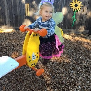 Child in costume on a playground seesaw