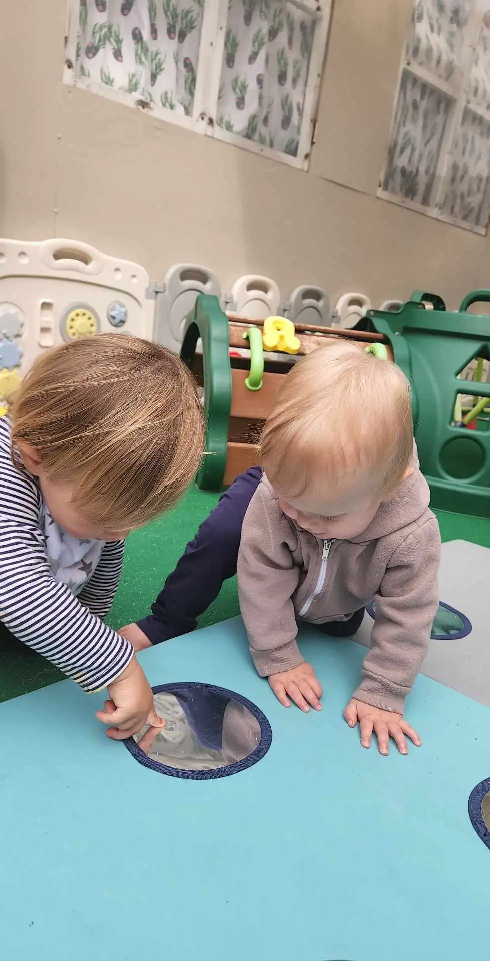 Two children playing on a blue surface