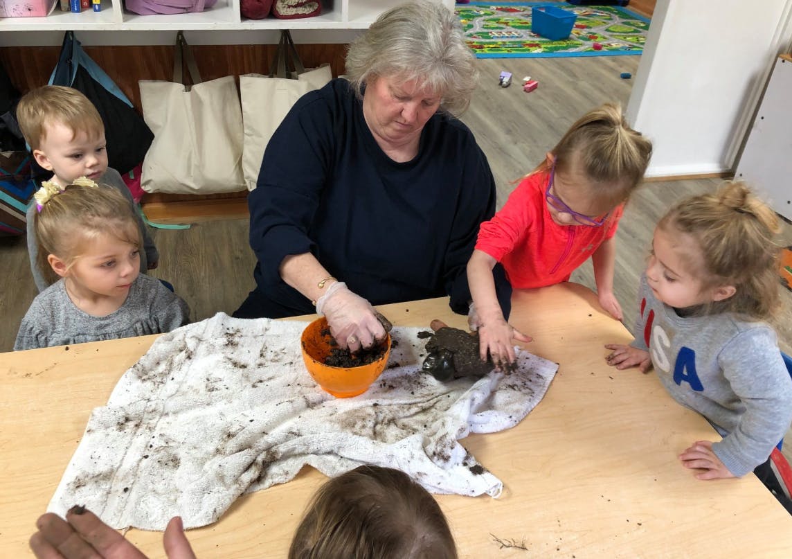 Adult and children playing with mud on a table