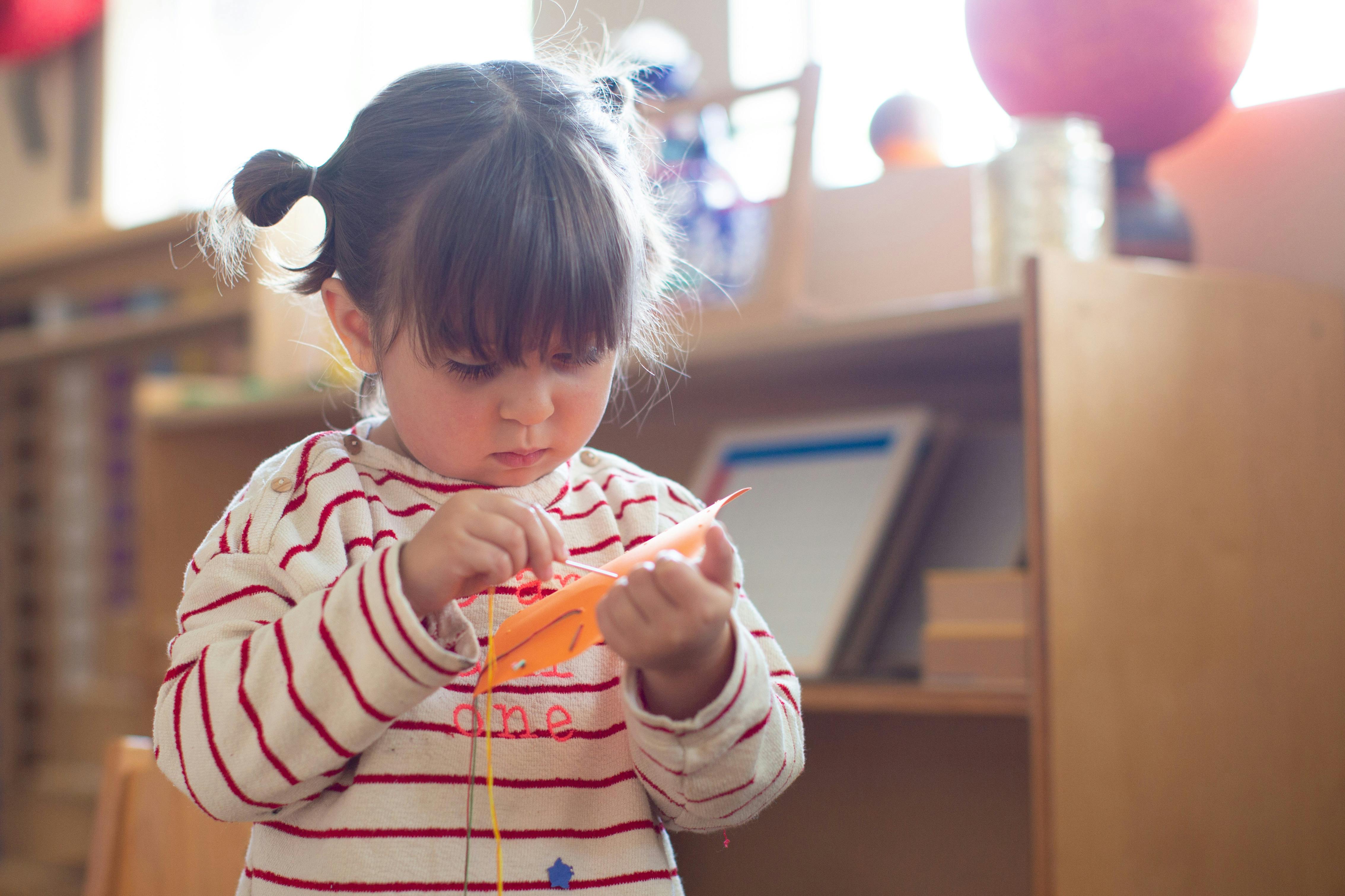 Child holding and looking at an orange feather