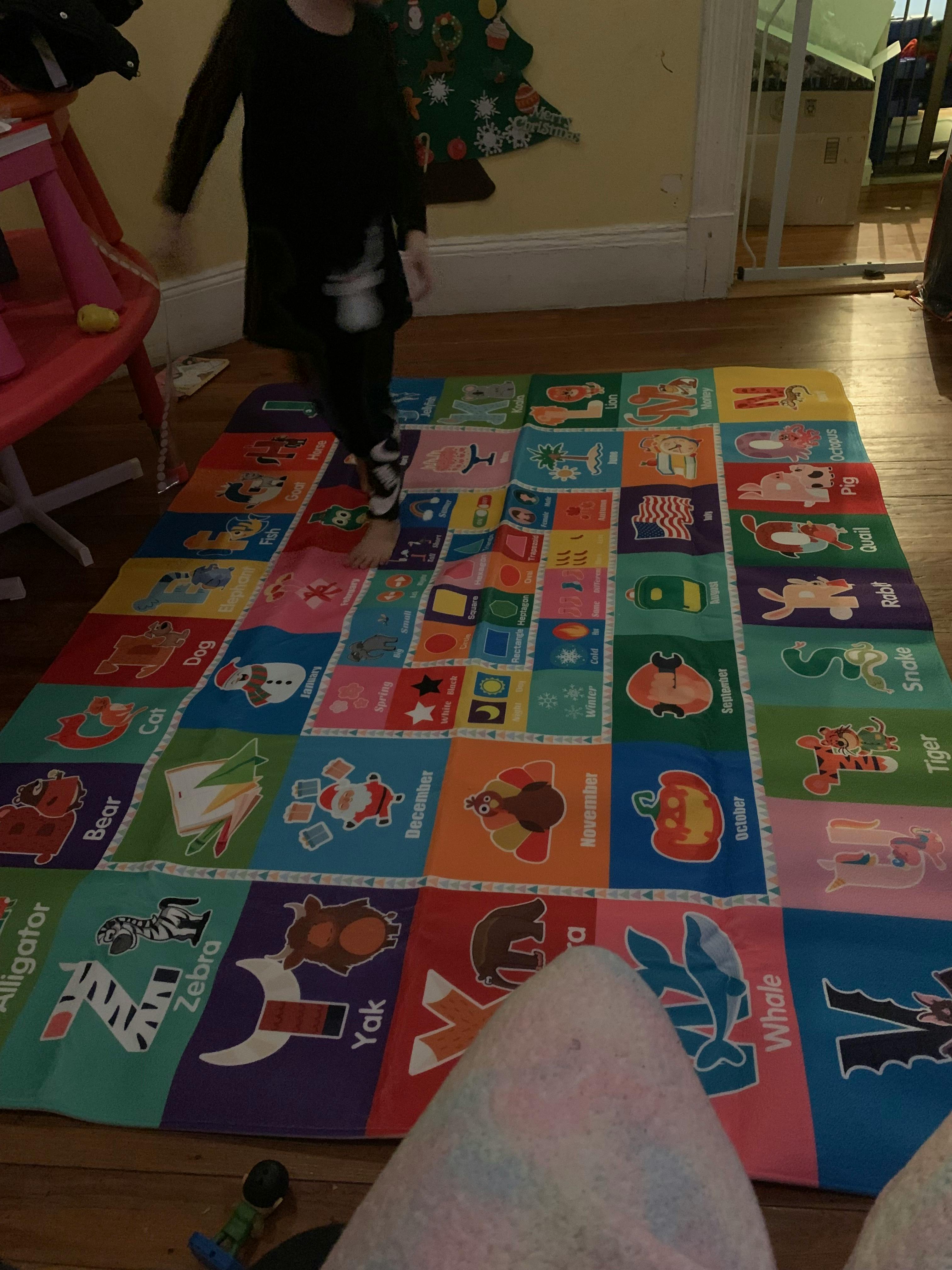 Child standing on a colorful alphabet playmat