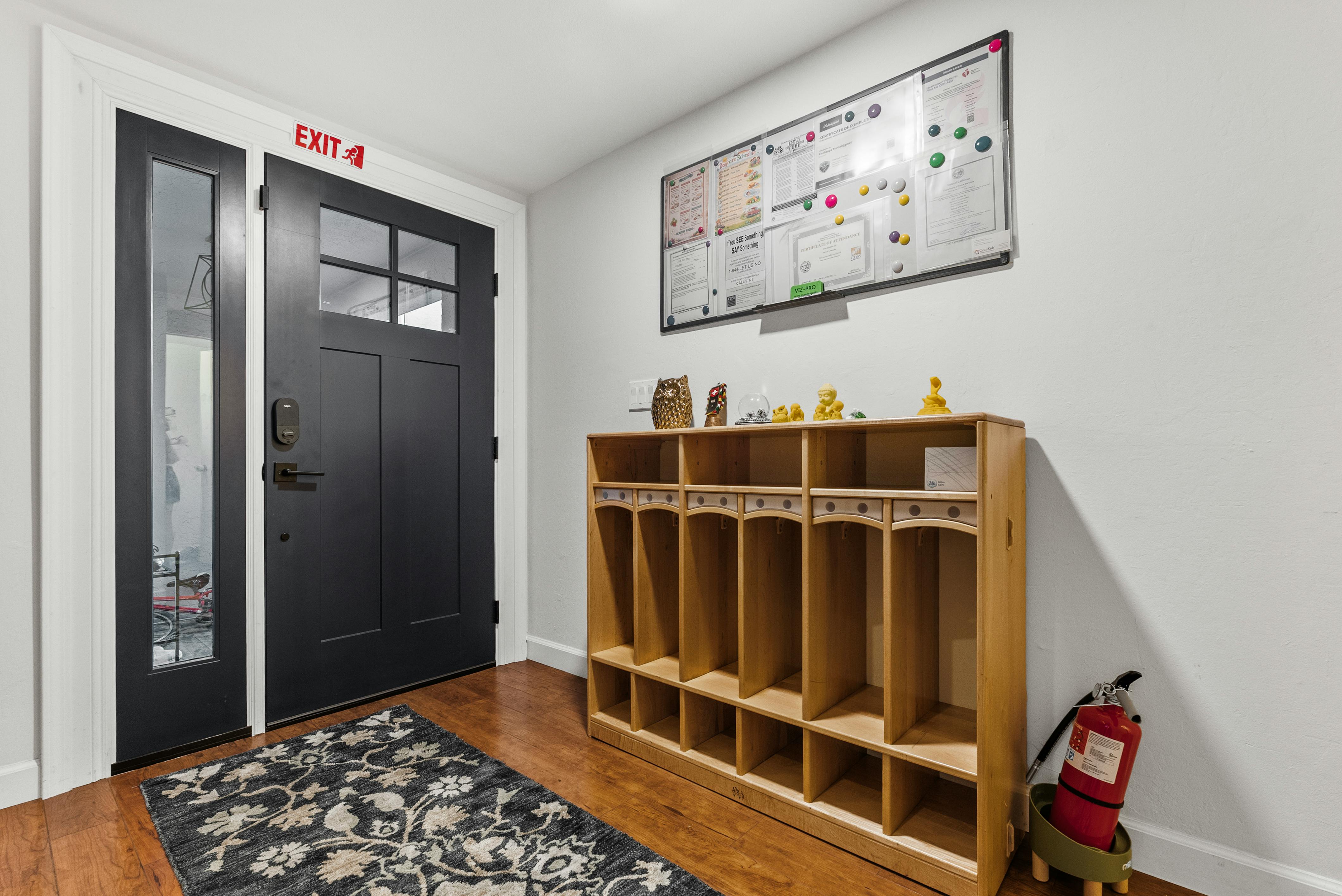 Entrance with a black door, an exit sign, and a wooden cubby shelf
