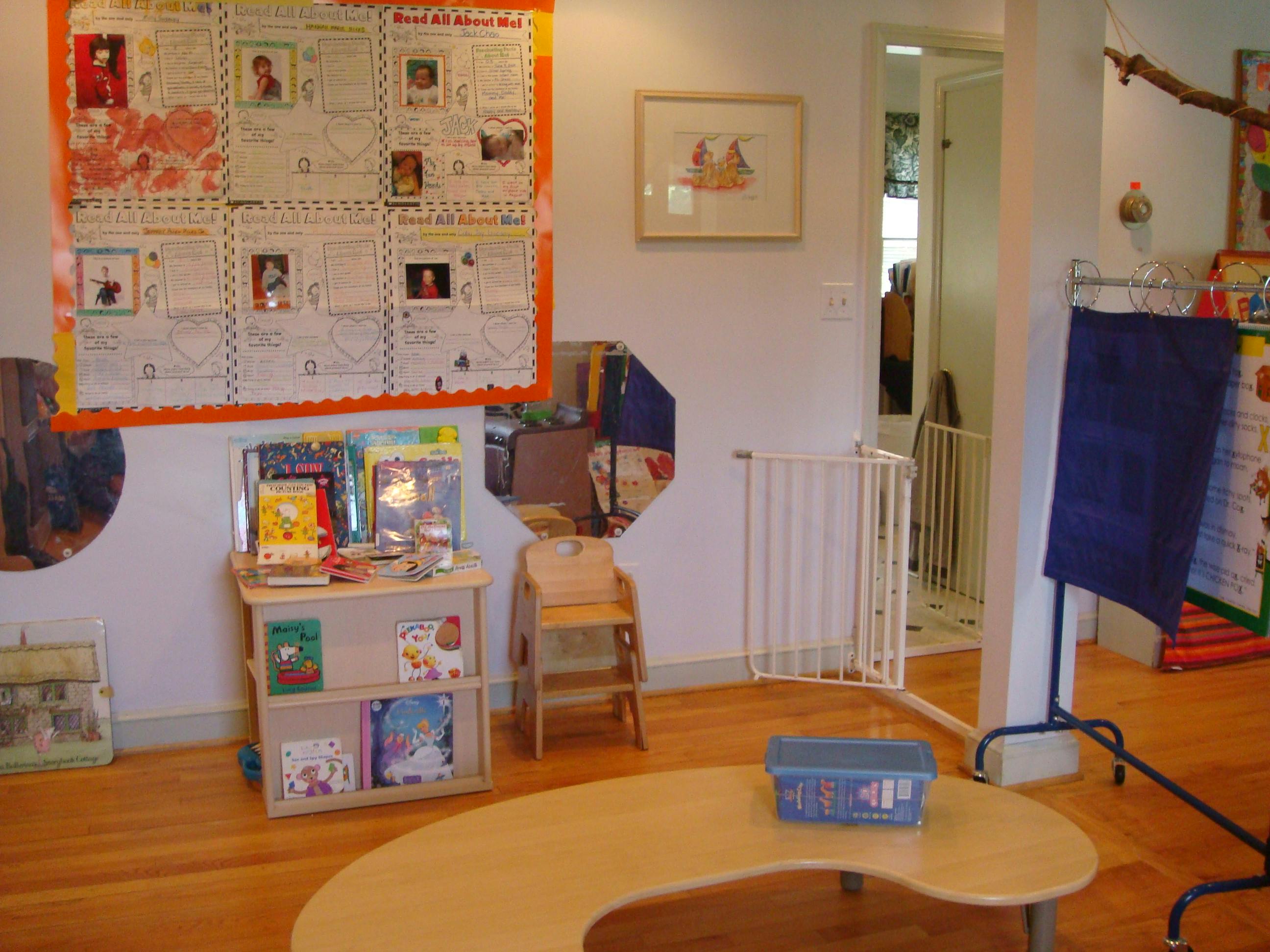 Classroom with a bulletin board, bookshelf, small table, and child safety gate