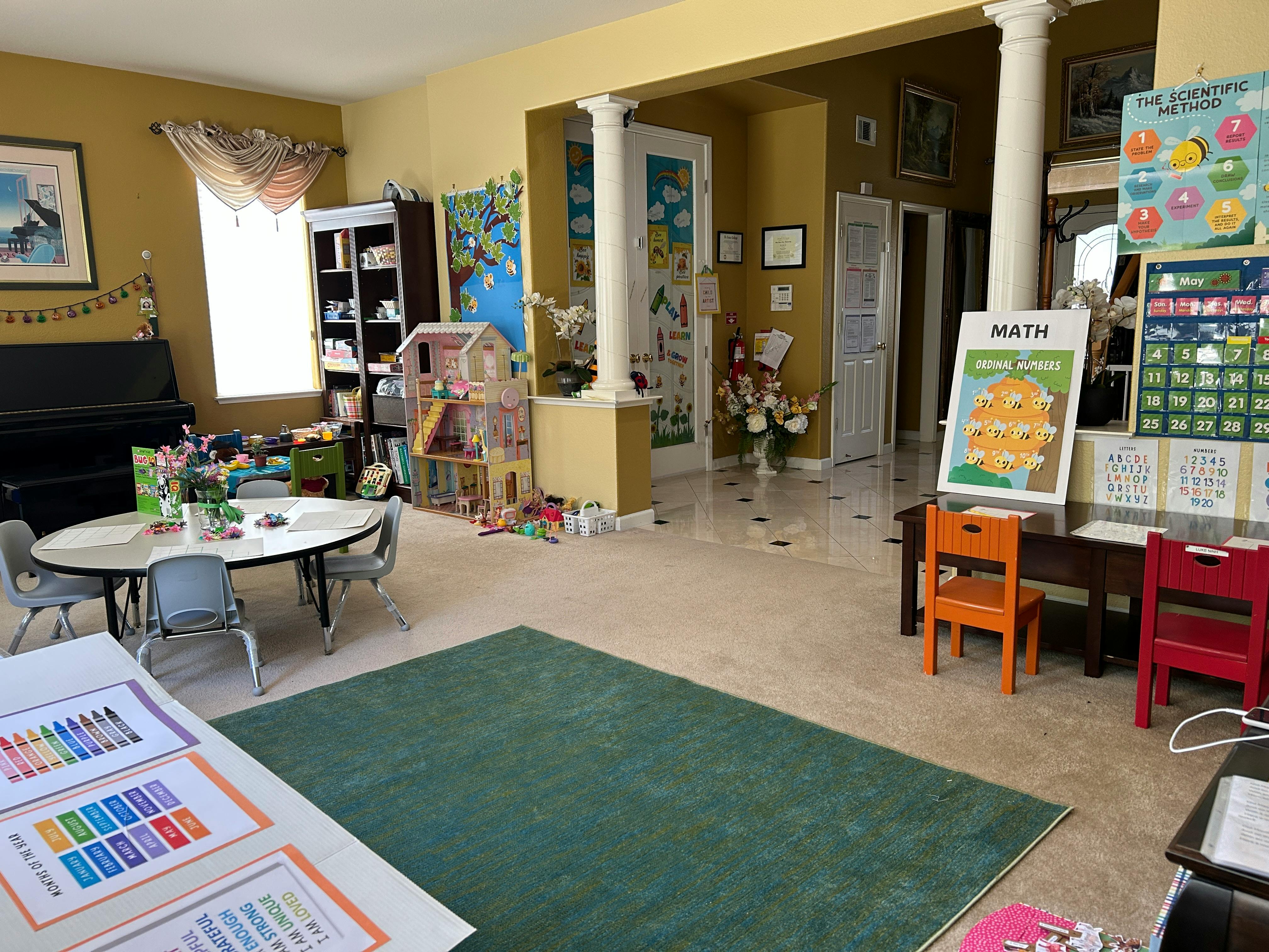 A room with a table and chairs, a piano, and a math poster