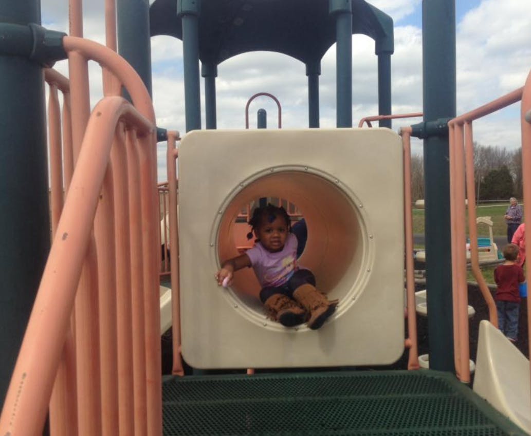 Child sitting in a round opening on playground equipment
