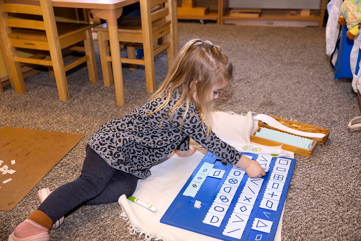 Child on floor playing with a blue letter board