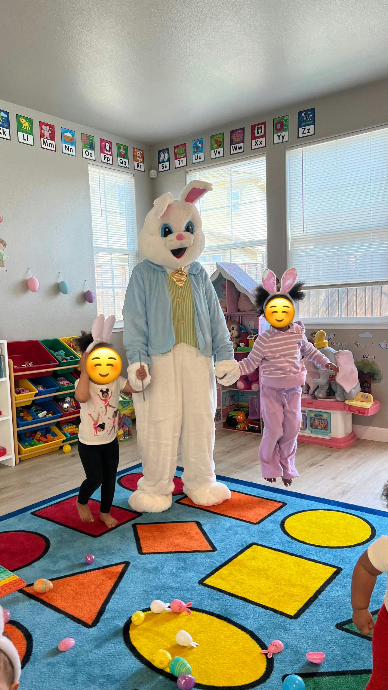 Person in bunny costume holding hands with two children in a classroom