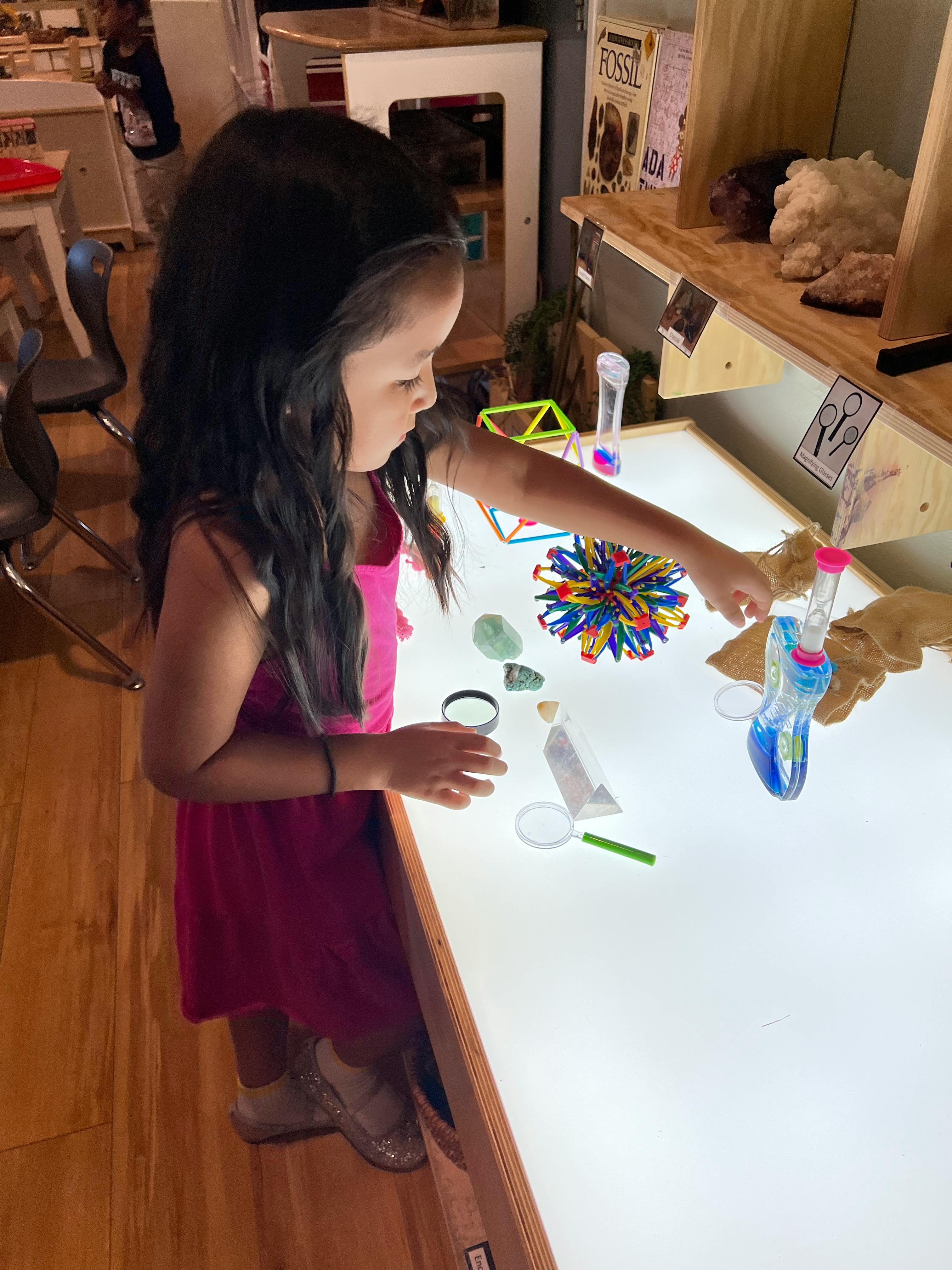Child playing with items on a light table