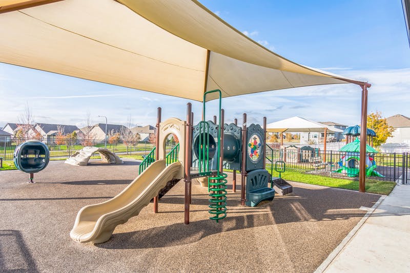 Playground equipment under a large shaded canopy