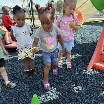 Three children playing with yellow rings on a playground