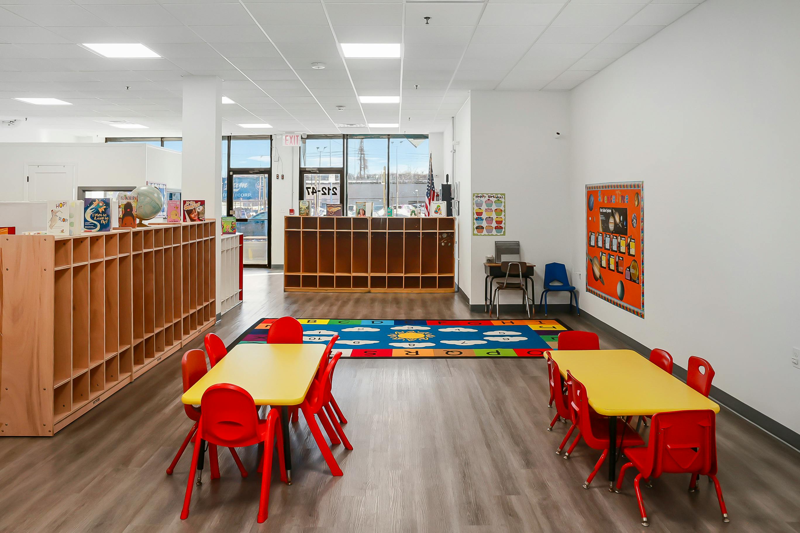 Empty preschool classroom with yellow tables and red chairs