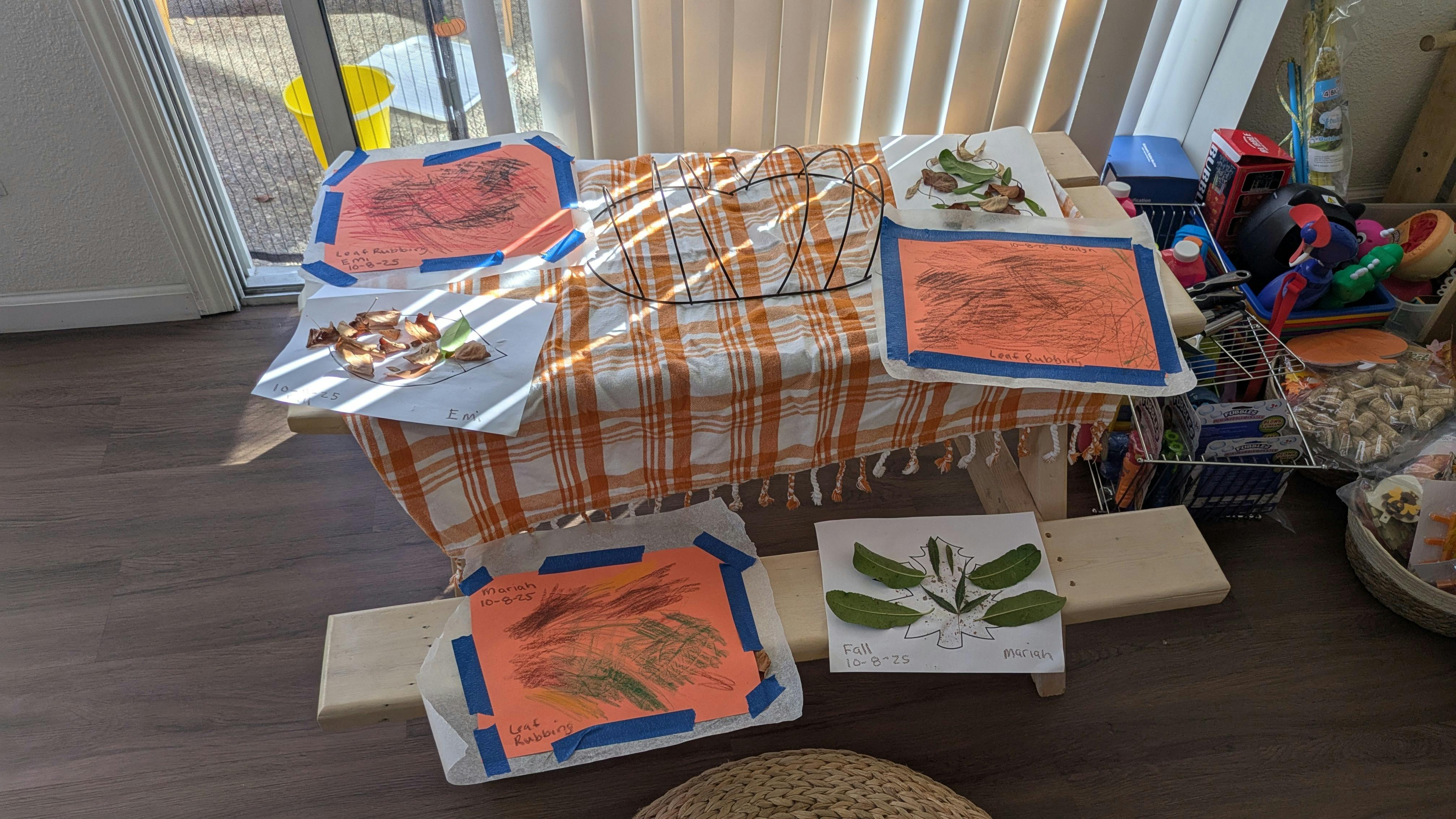 Table with children's drawings and leaves taped to paper