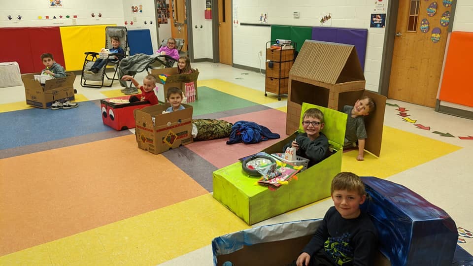 Children playing in cardboard boxes in a room