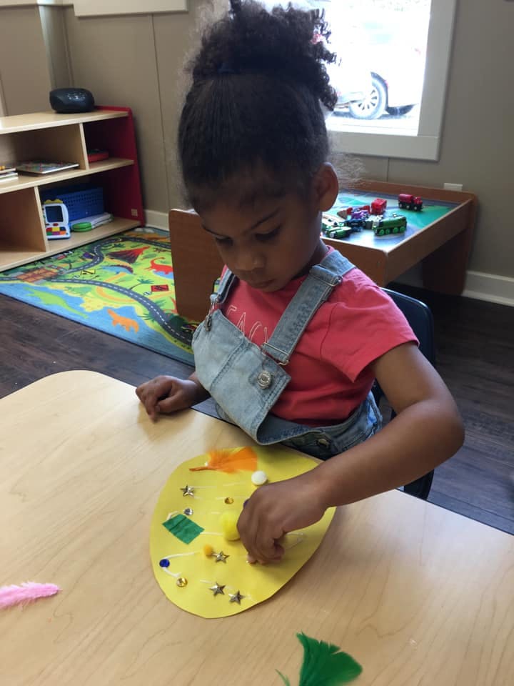 Child in a classroom decorating a yellow paper shape
