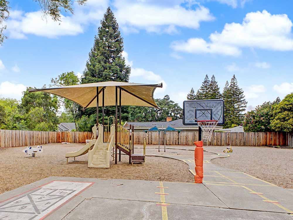 Playground with slides, shade structure, and a basketball hoop