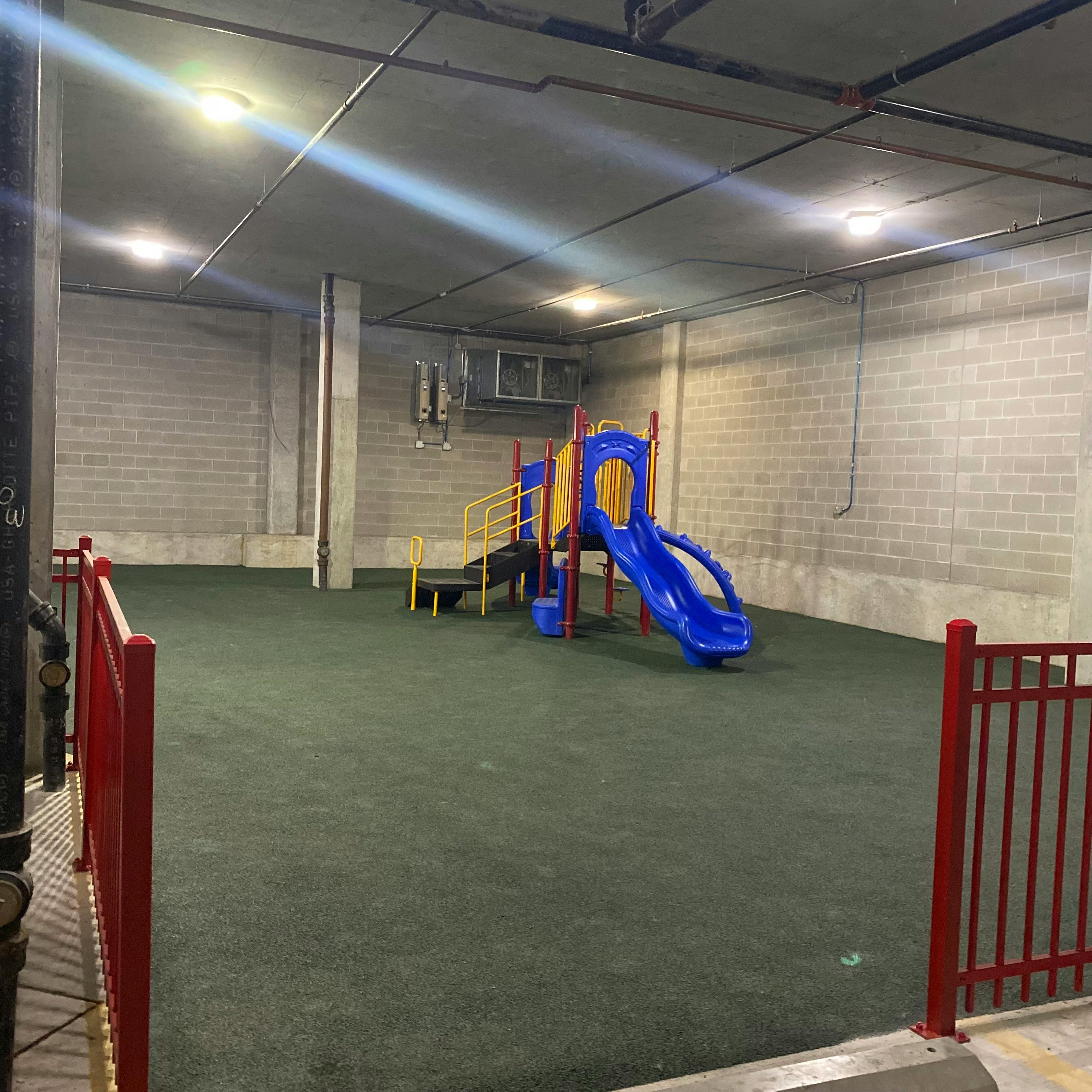 Indoor playground with blue and yellow slide structure on green flooring