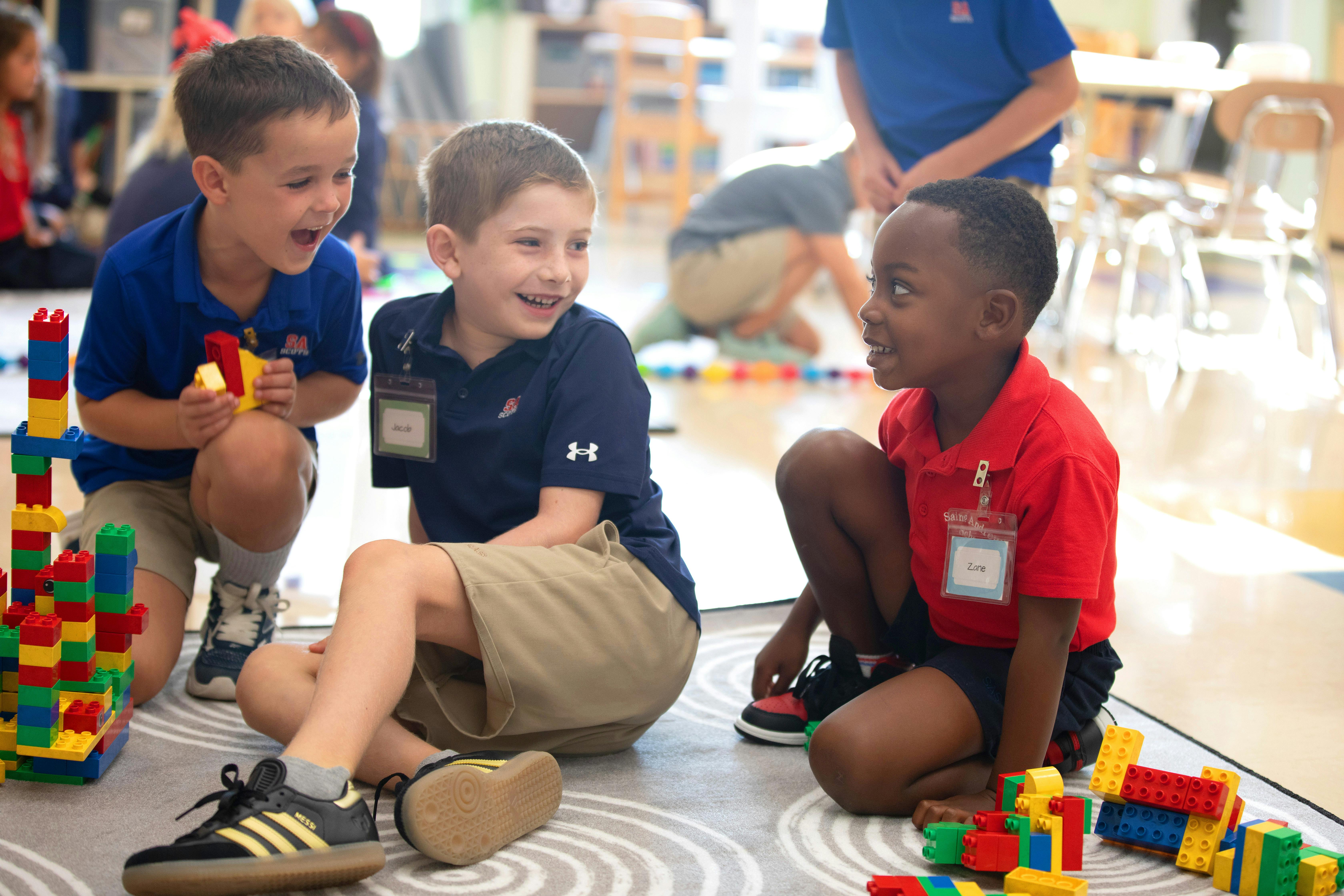 Three children playing with colorful building blocks on the floor
