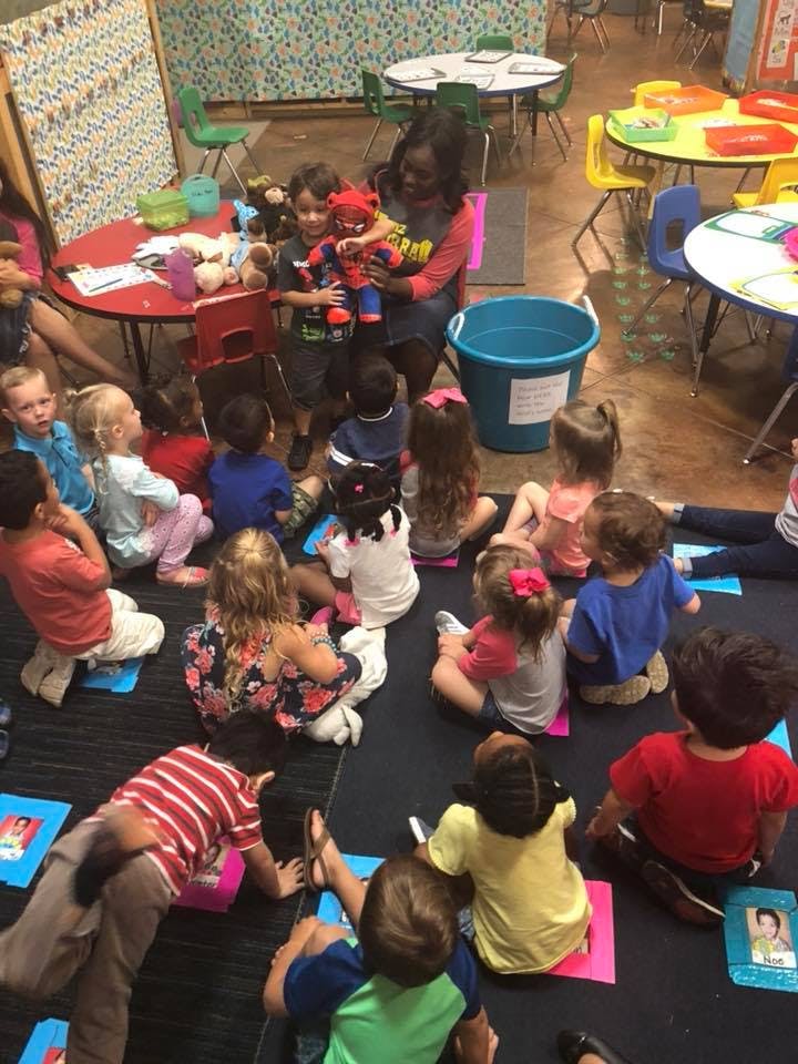 Adult holding a stuffed animal for a child surrounded by other children