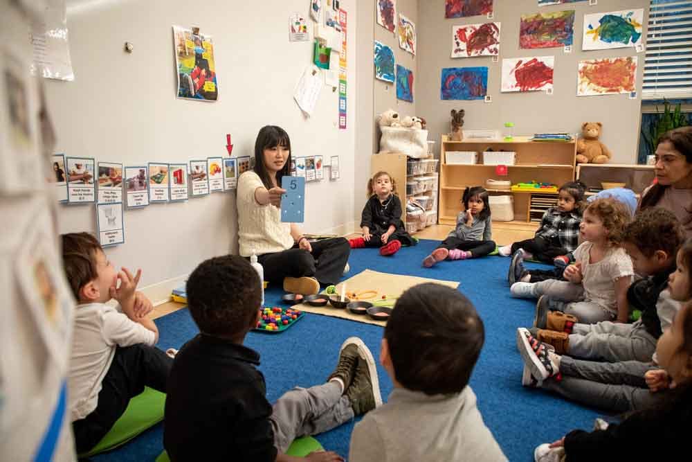 Adult showing a book to children sitting on the floor in a classroom