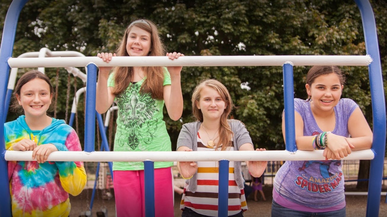 Four teens on playground equipment