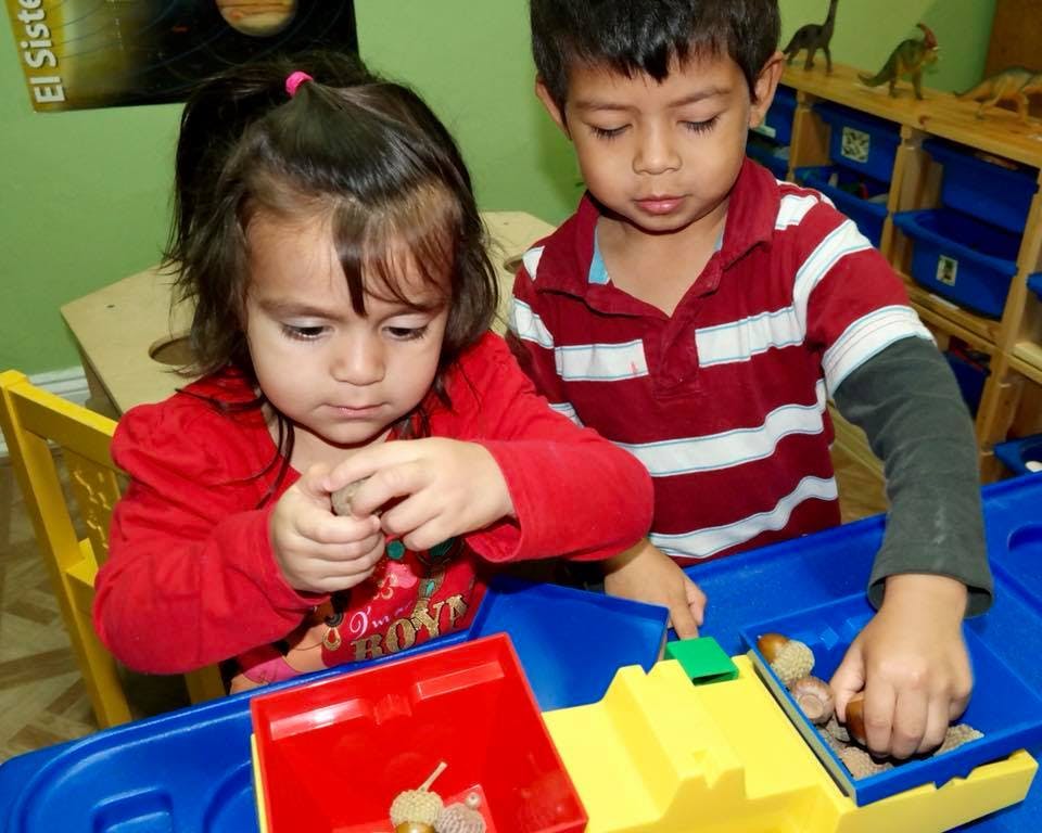Two children playing with small objects at a table