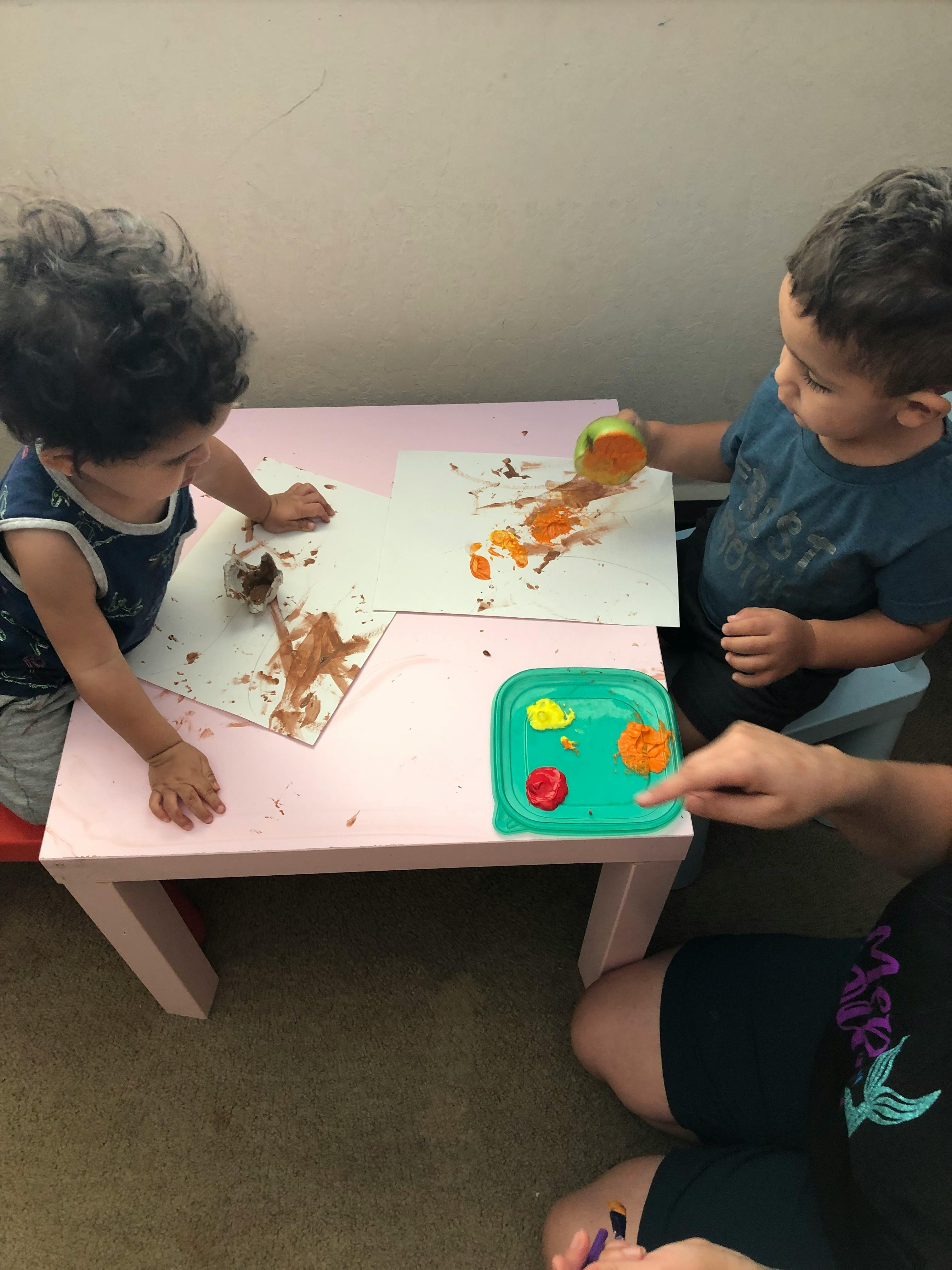 Two children painting at a small table