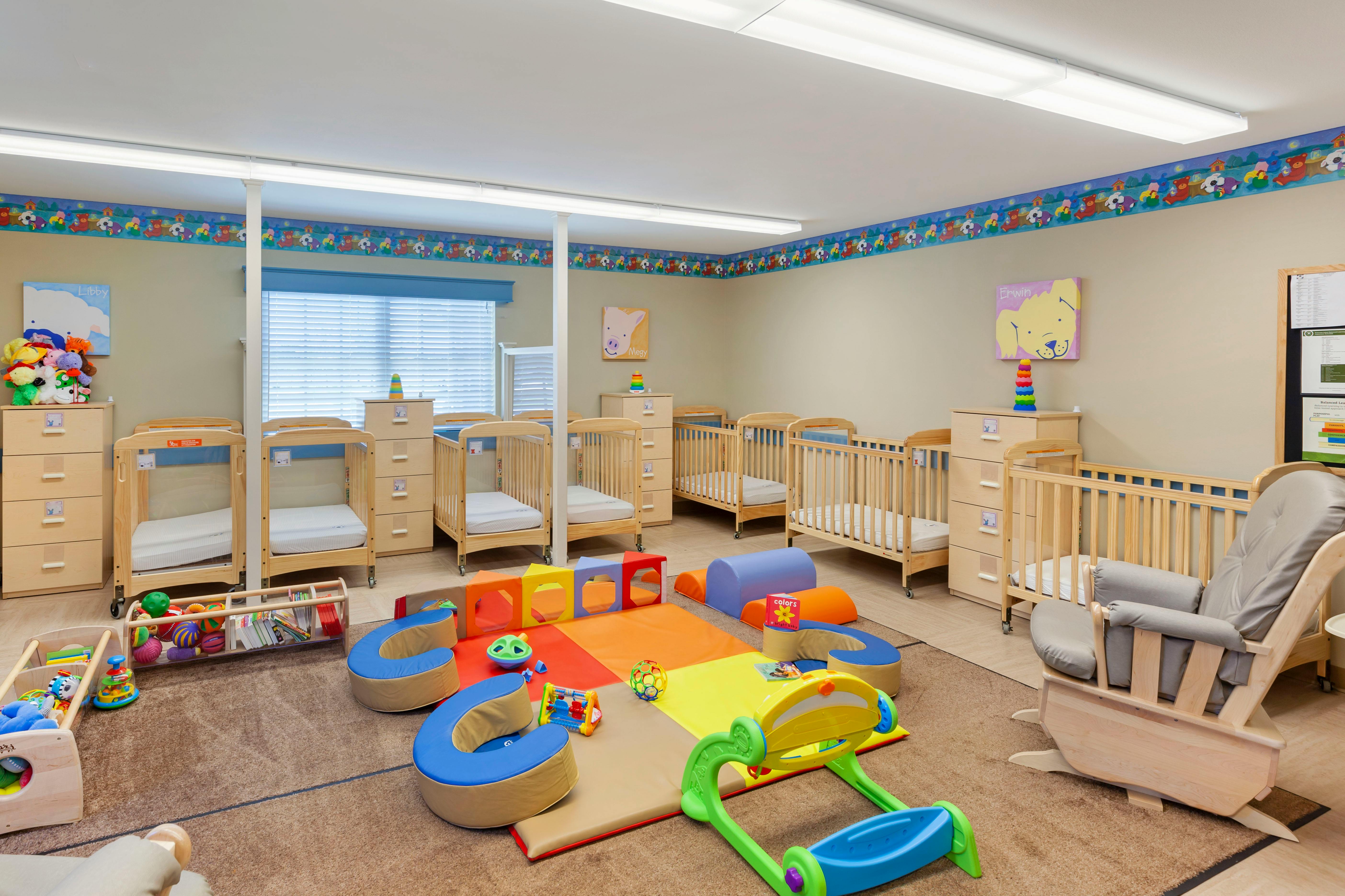 cribs, changing tables, and infant play equipment in a nursery room