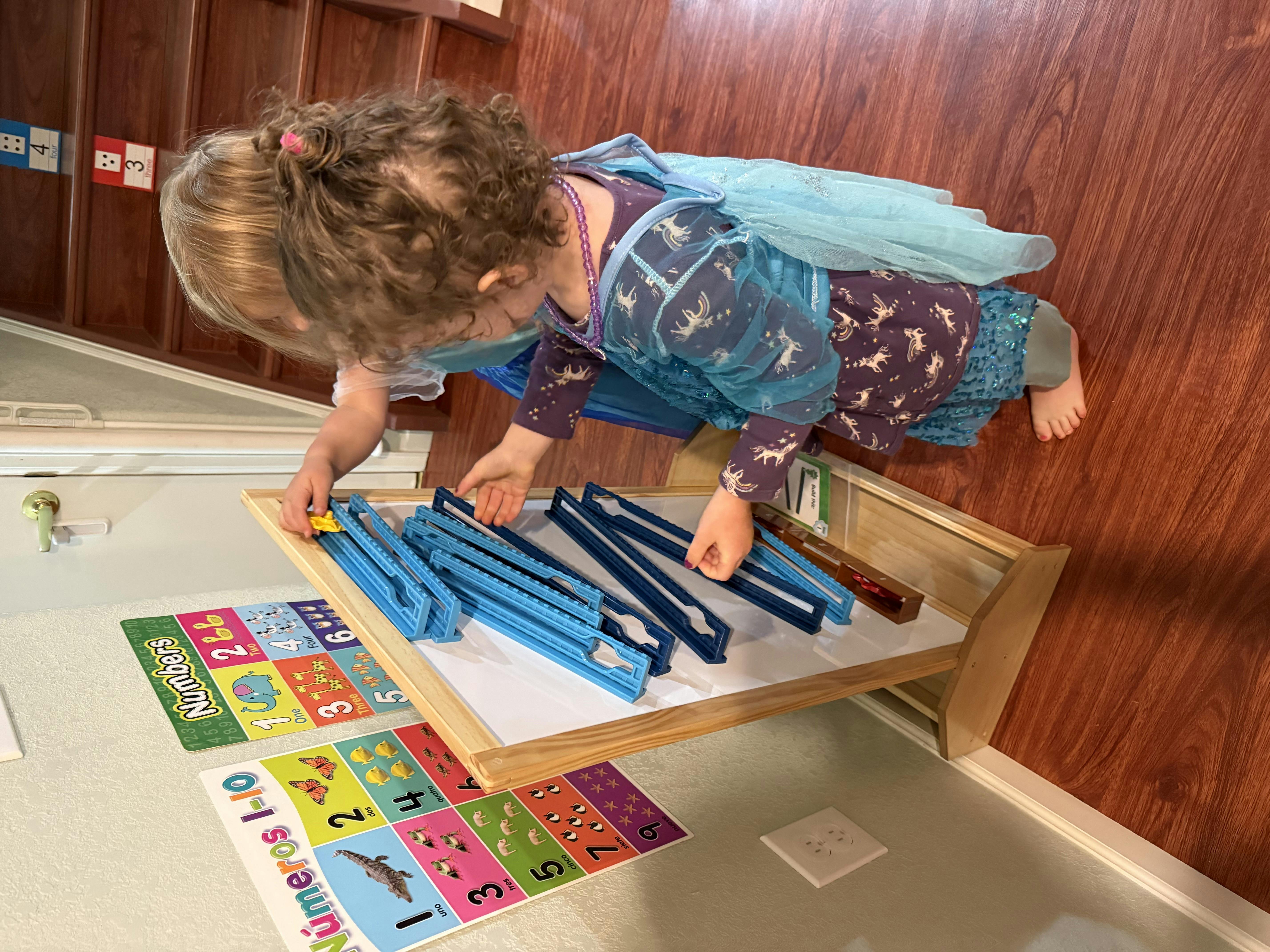 Child playing with blue toy car tracks on a table