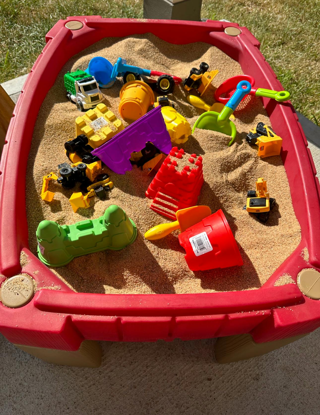 Sandbox filled with sand toys including various colorful toys