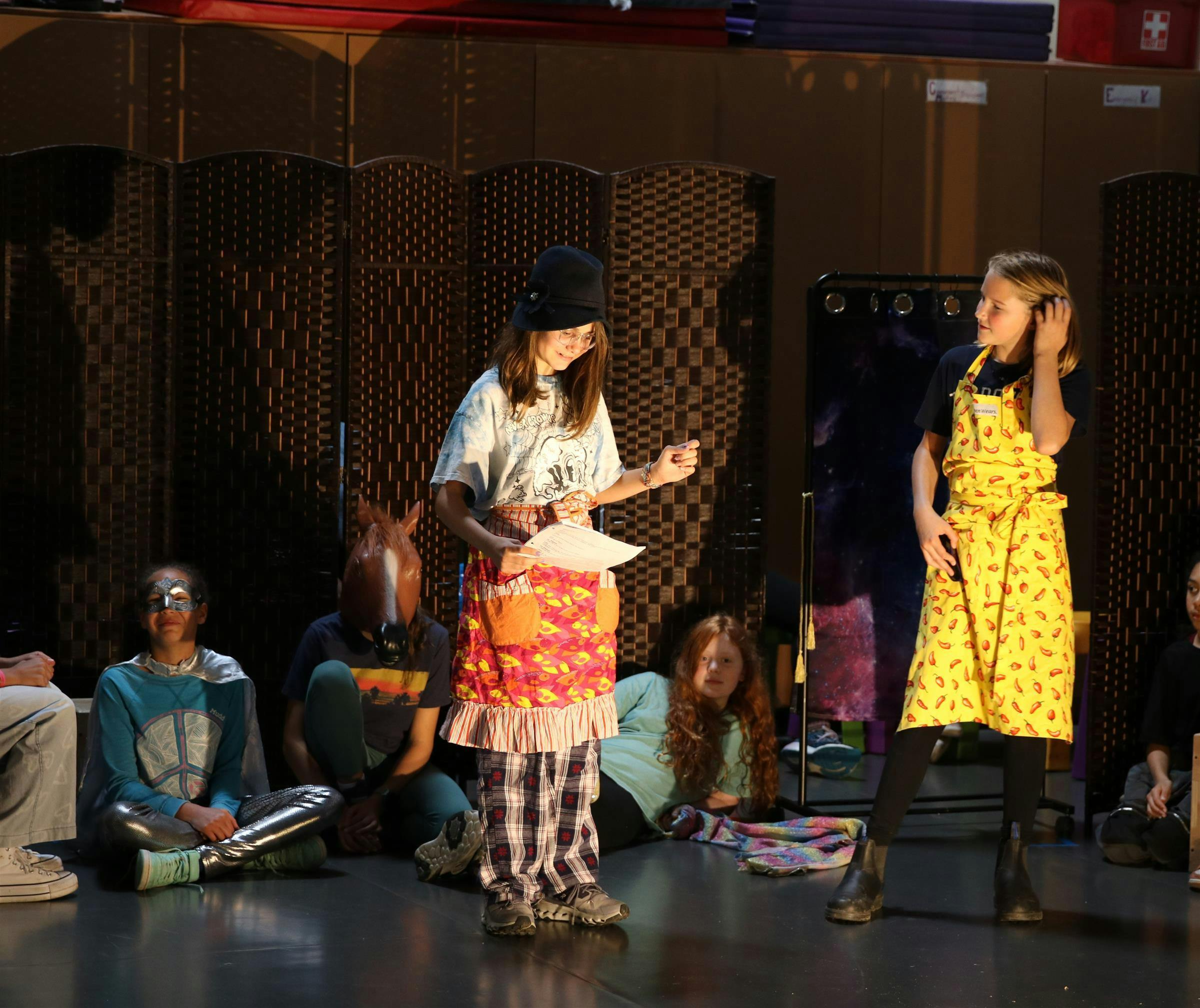 Child actors rehearsing on a stage with two standing and three seated