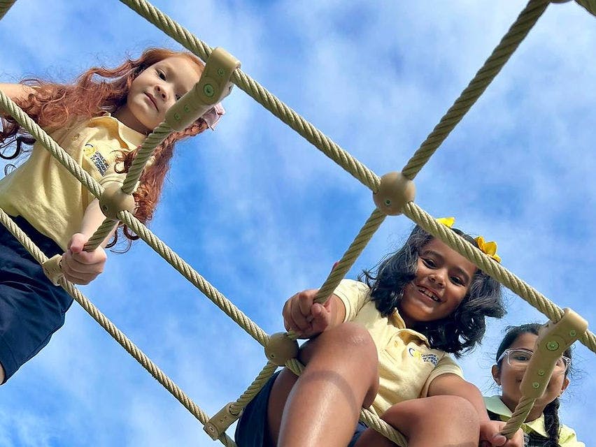 Three children climbing on a rope net