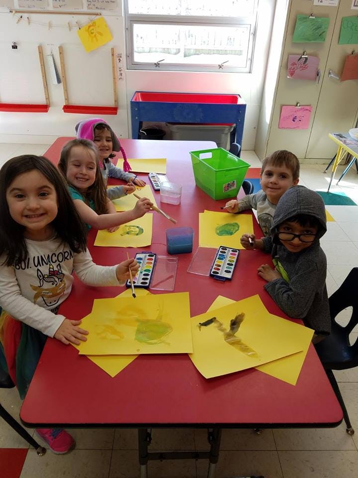 Children painting at a table in a classroom