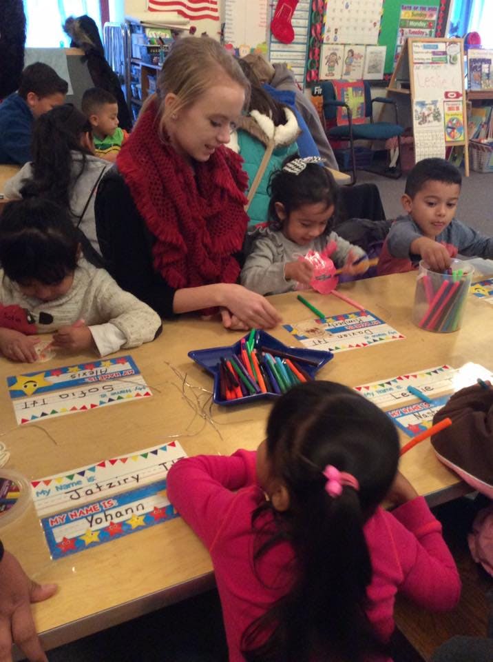 Adult and children coloring at a table in a classroom