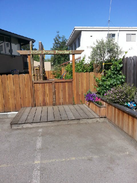 Wooden gate with "Little Beans Preschool" sign above it