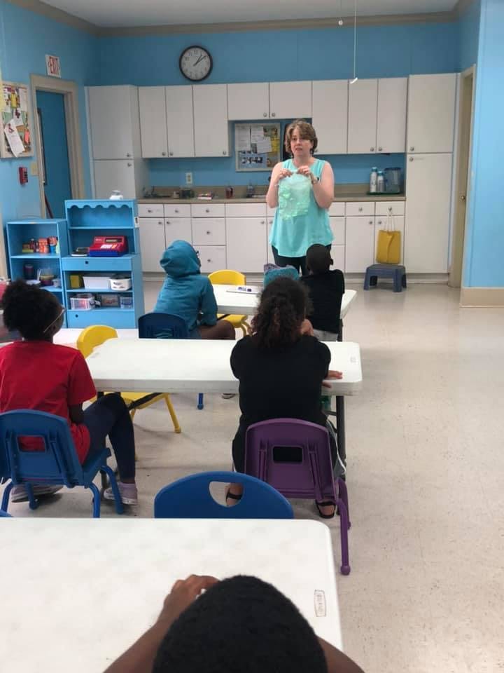 Adult person standing in front of seated children in a classroom