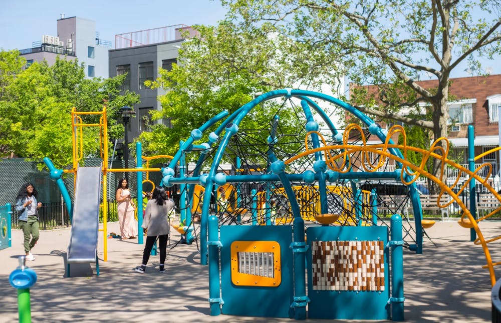 People on a playground with a slide and climbing structures